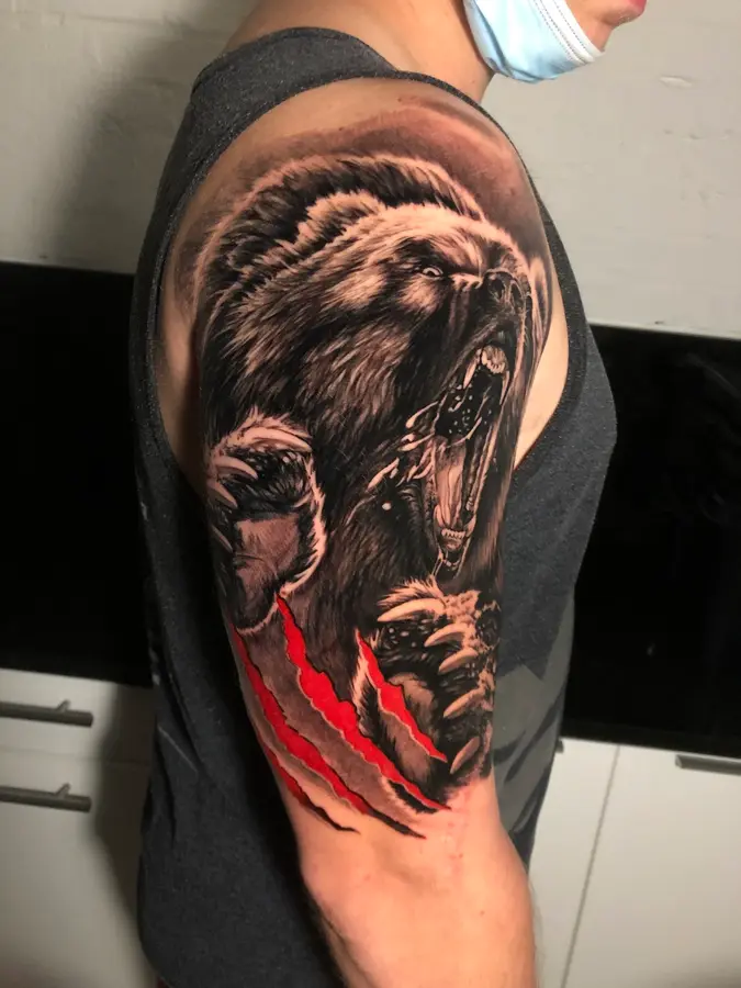 Realistischer Bär in Black & Grey mit roten Krallenspuren auf dem Oberarm